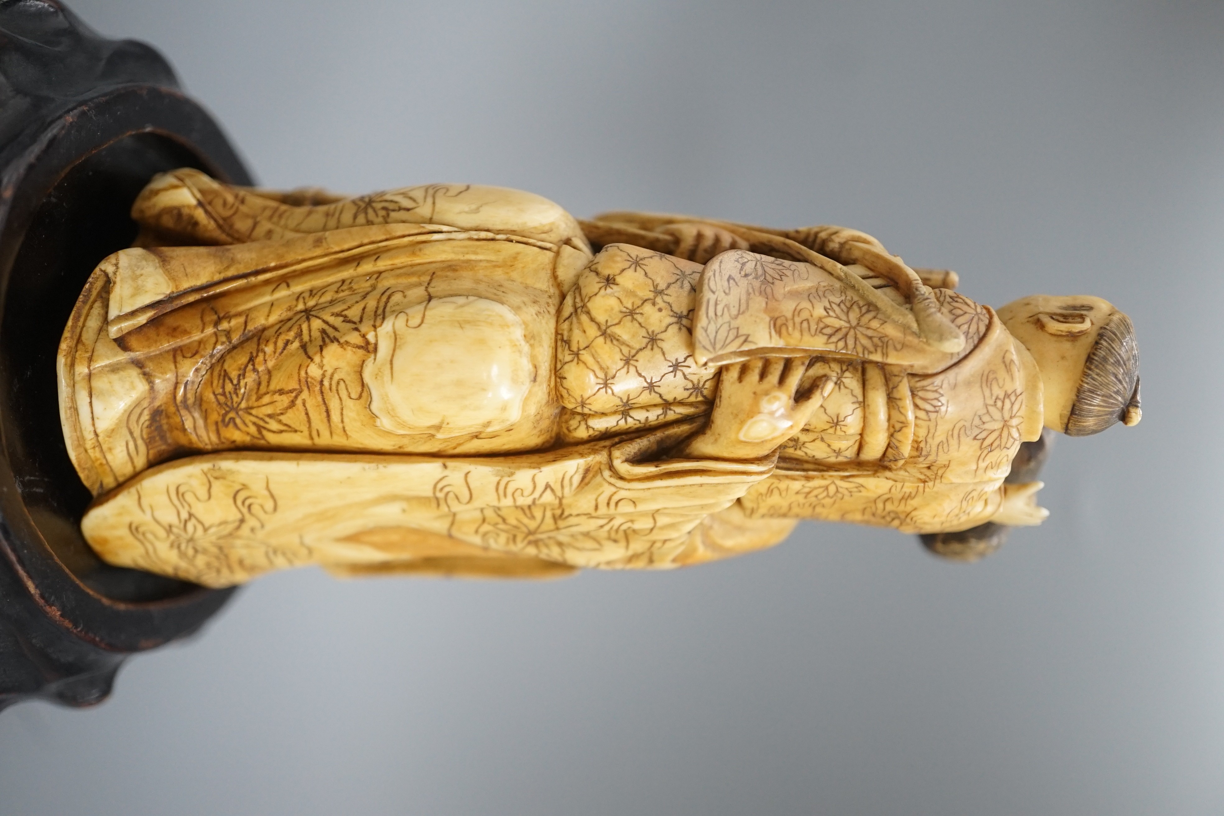 A Japanese ivory okimono of a lady holding a boy with a bow and arrow, Meiji period, restoration 12cm, wood stand
